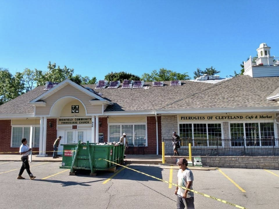 Community church roofing project mid-installation with shingles staged