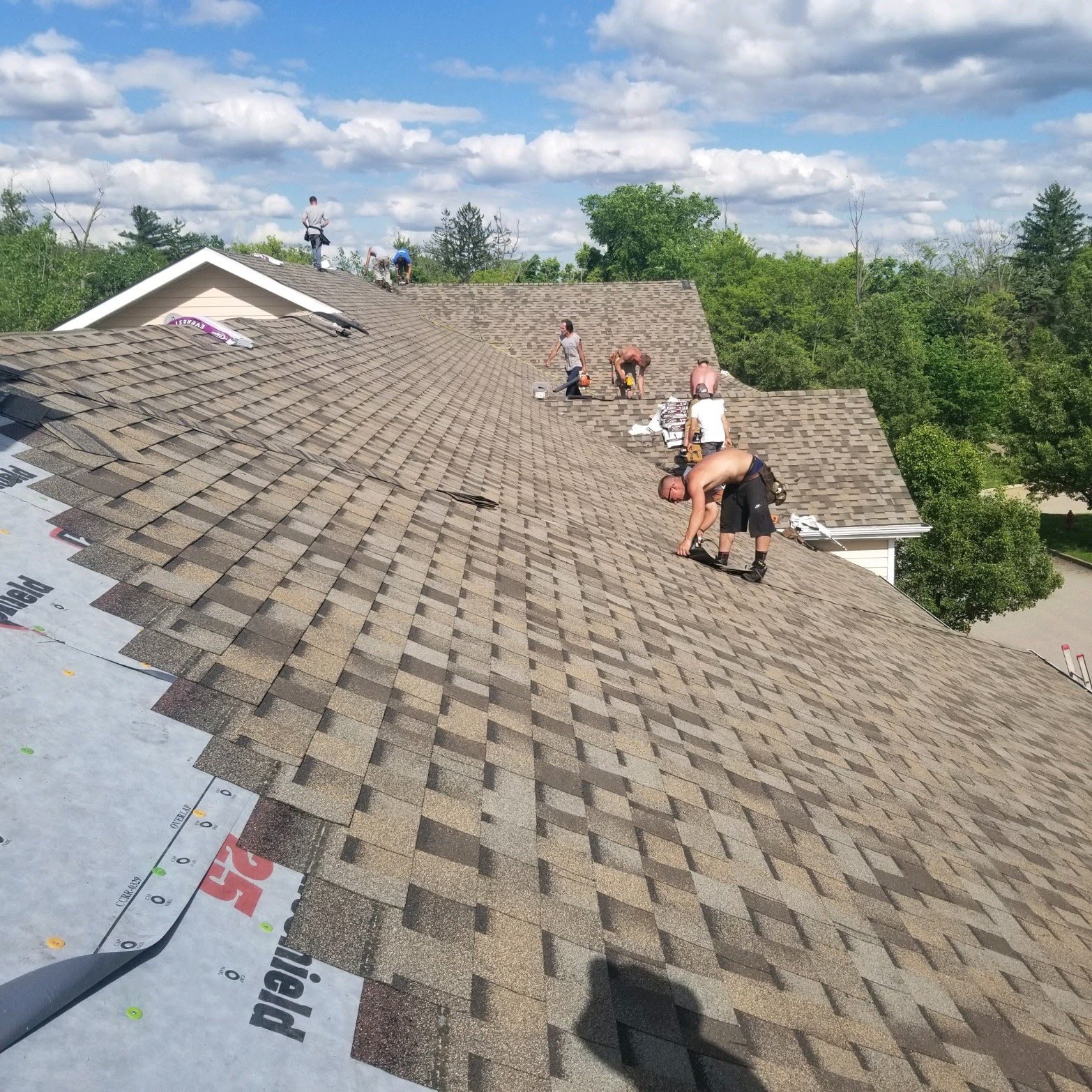 Full residential asphalt-shingle re-roof in progress with multiple crews on-site